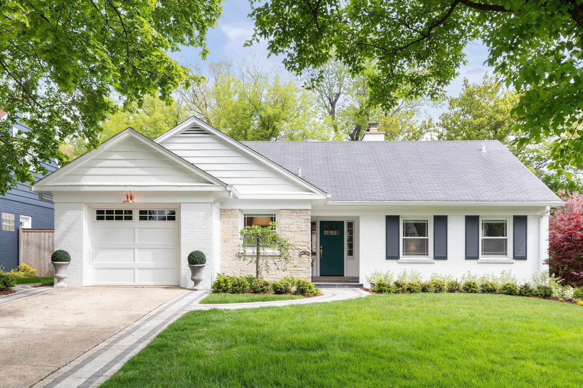 Beautiful suburban home with white brick and stone siding and landscaping